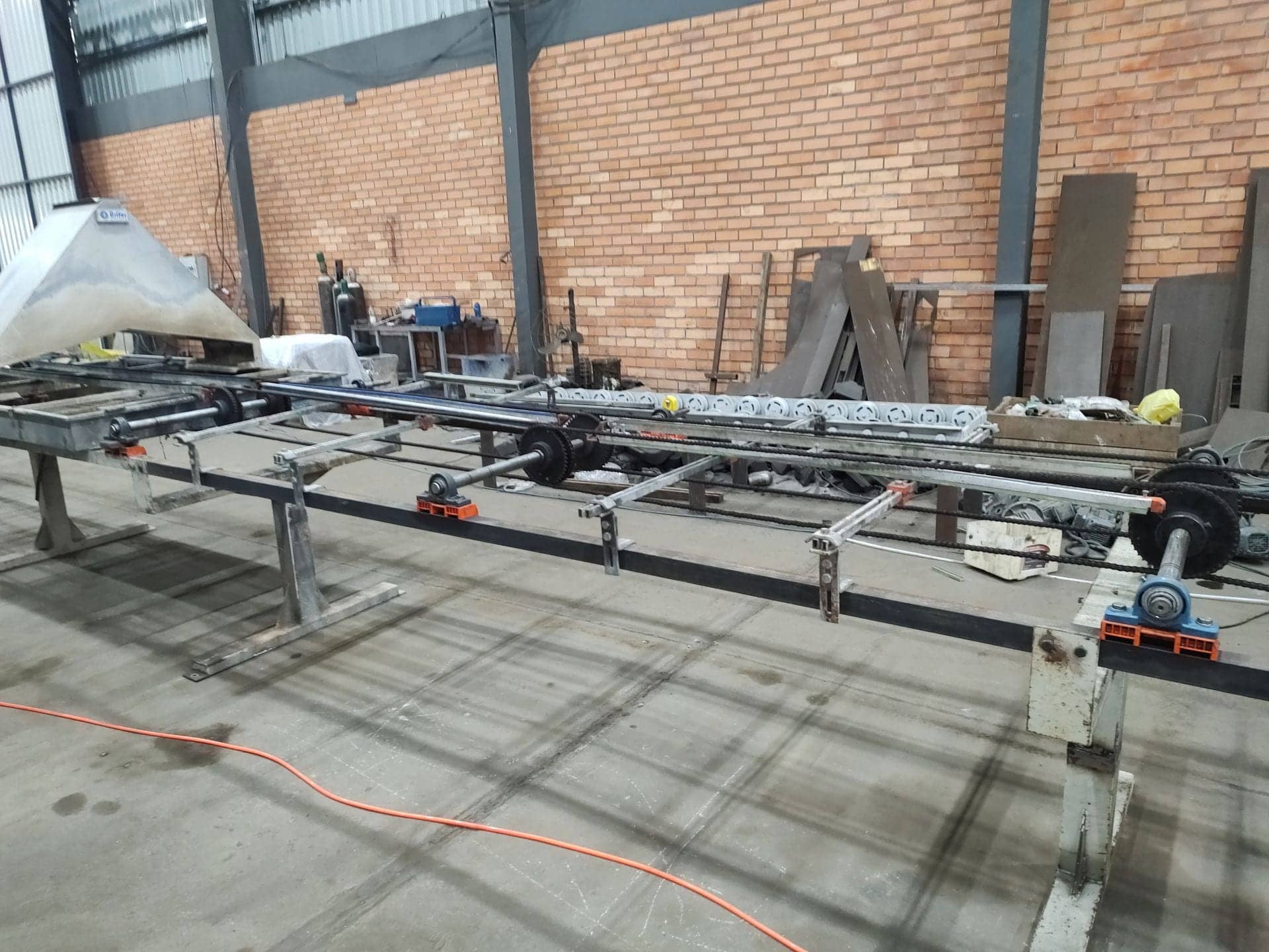 Linha transportadora de roletes e correntes em montagem dentro de galpão industrial
